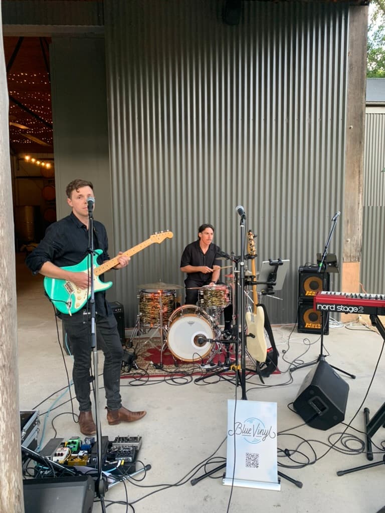 Blue Vinyl guitarist and drummer performing at a wedding in a barn venue