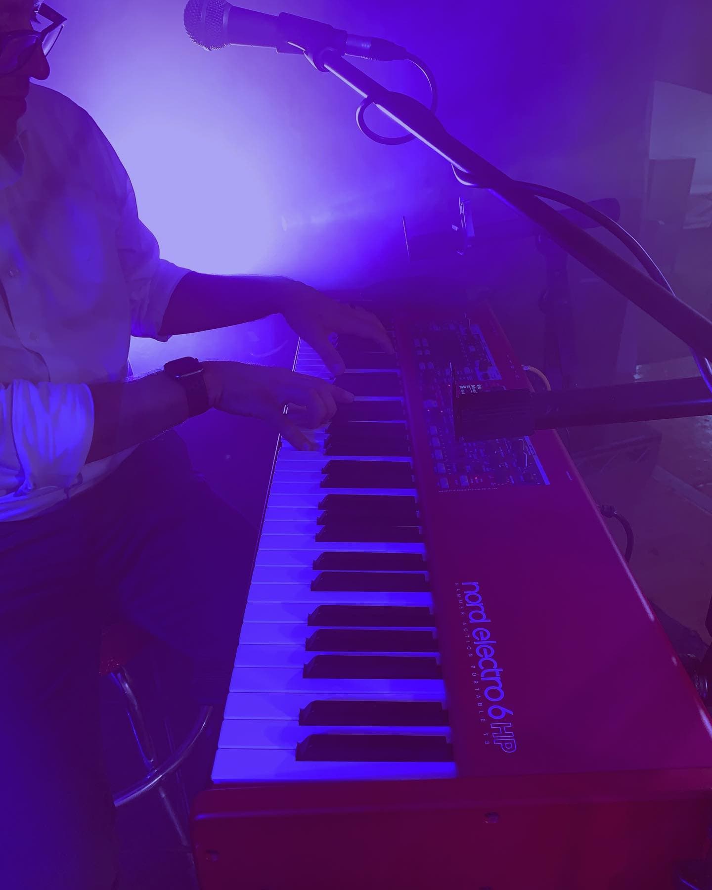 Blue Vinyl keyboardist playing Nord Electro under purple stage lighting